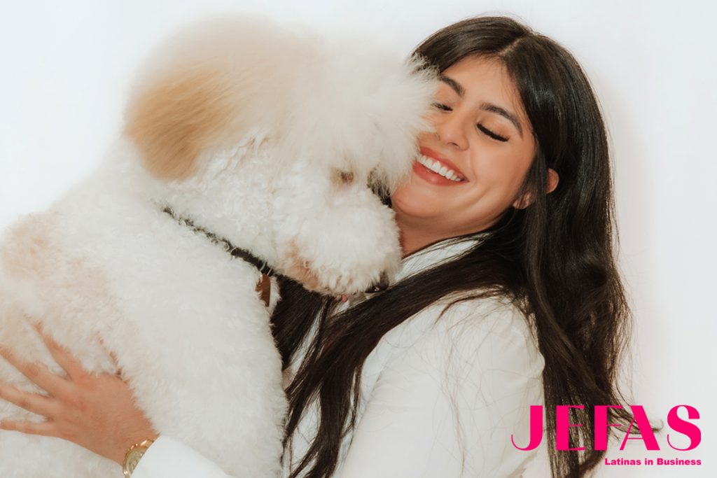 Side profile of white dog in front of woman's face smiling down at the dog